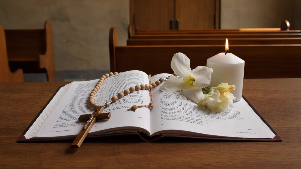 Terço sobre uma Bíblia aberta ao lado de uma vela acesa, com luz suave de igreja ao fundo