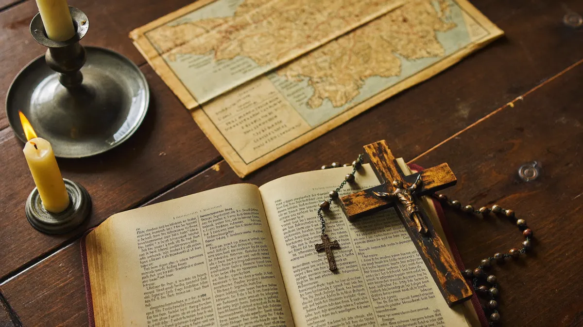 Bíblia aberta, rosário, vela acesa e mapa antigo sobre uma mesa de madeira, lembrando a missão evangelizadora de São Antônio Maria Claret